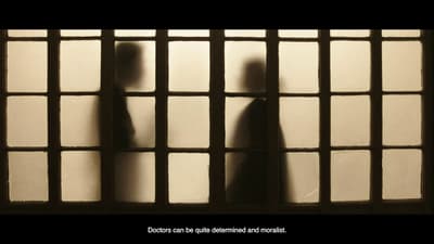A film still in which two figures face each other behind a paneled screen.