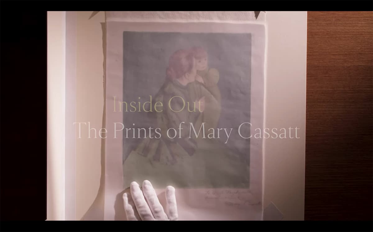 A gloved hand holding a print of a woman with a child, overlaid with text about Mary Cassatt's prints.