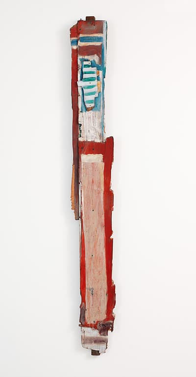 A scrap of wood painted in red, blue, and pink against a white background.
