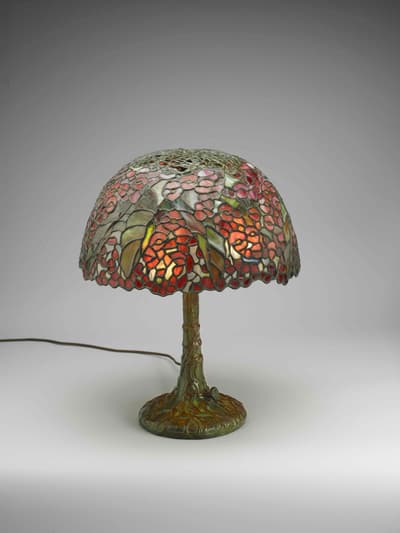 Stained glass table lamp with floral design and tree trunk-style base.