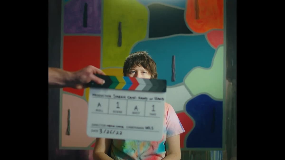 Artist Sarah Cain behind a clapperboard in front of an installation of her painting