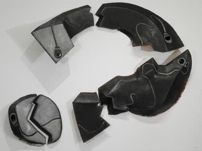 Sculptural wall installation of a series of pieces forming a broken question mark.