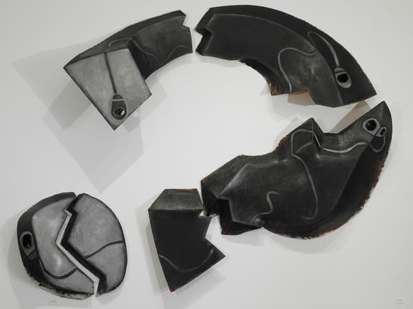 Sculptural wall installation of a series of pieces forming a broken question mark.