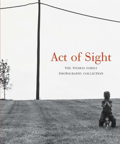 Book cover art with "Act of Sight" in red lettering and "The Tsiaras Family Photography Collection" as a subtitle. The cover art is a black and white picture of a boy sitting on a mannequin head in a lawn with a power line and tree in the background.