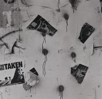 A weathered wall with torn posters and spray paint drips.