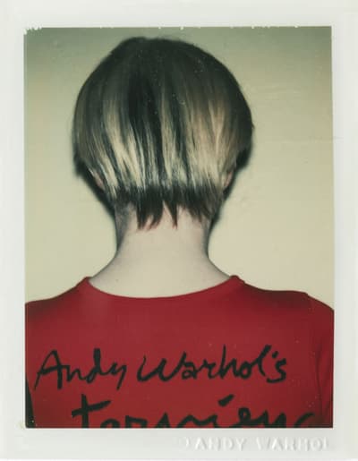 Back view of a person with short hair wearing a red shirt with black text.