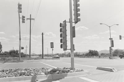 Black and white photo of a traffic intersection with multiple traffic lights and utility poles.
