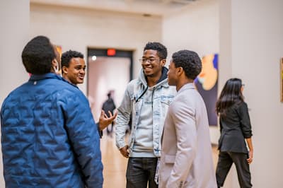 A group of male students talking to each other in a gallery