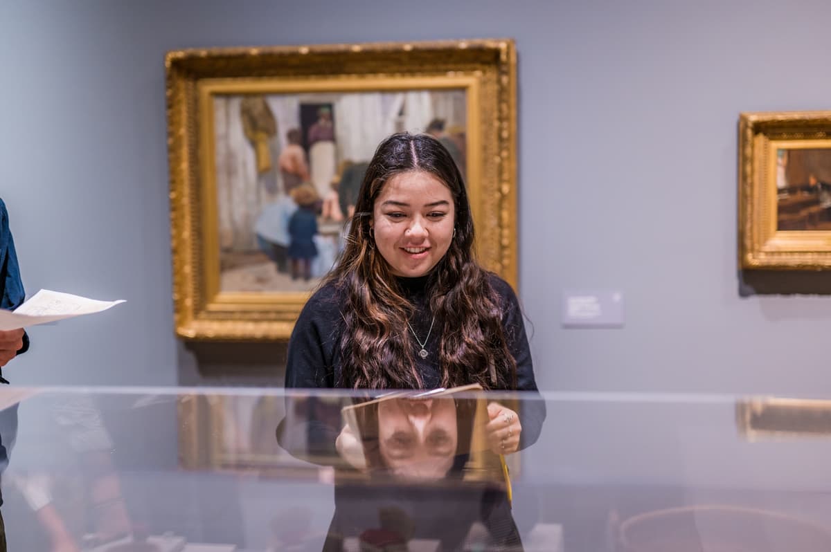 Woman smiling in an art gallery in front of a painting.