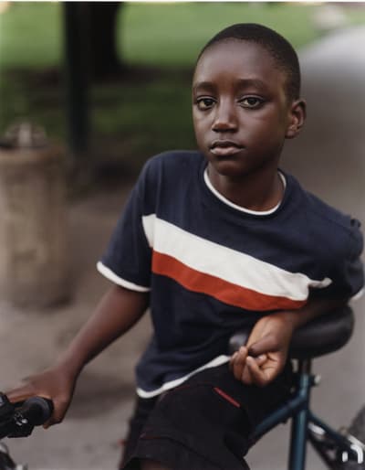 Coloful photograph of a young boy posing with his bike.