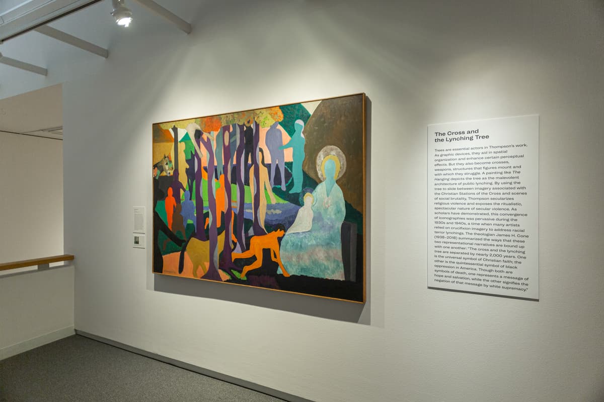 Large painting of figures in bright colors next to wall text titled "The Cross and Lynching Tree."