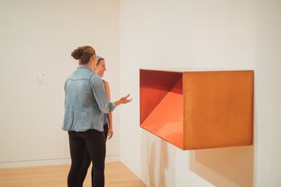 Two women talking to each other in front of a hanging sculpture