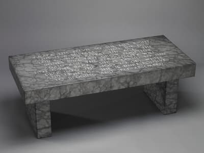 A granite bench by Jenny Holzer with engraved text titled Under a Rock: Crack the Pelvis, 1986.