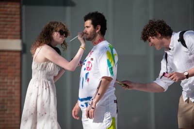 Two students painting on a third student