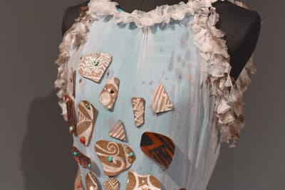 Top of a blue dress attached geometric patterned fabric pieces in neutral and earthy tones.