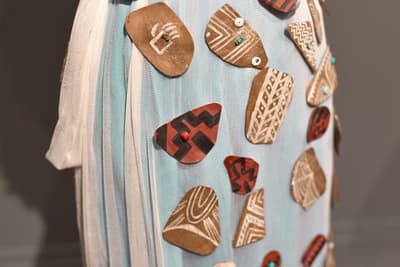 Textile with attached geometric patterned fabric pieces in neutral and earthy tones.