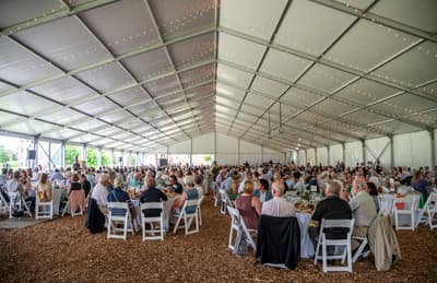 Event tent filled with seated guests listening to remarks at Colby.