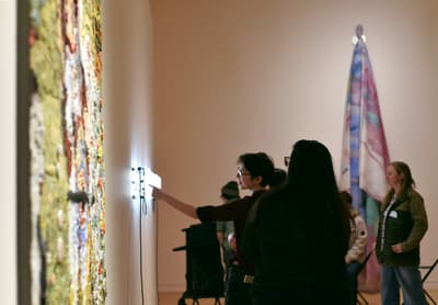 Student gesturing towards neon light artwork.