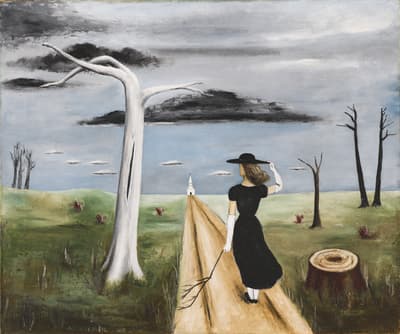 A woman in black walks on a dirt path in a surreal landscape with a white, leafless tree and cloudy sky.
