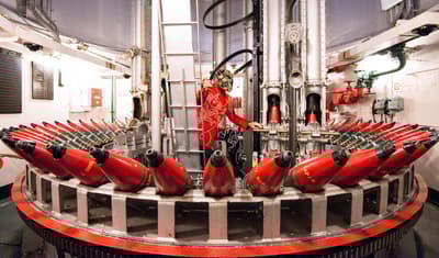 Industrial structure with red cylindrical components and central figure.