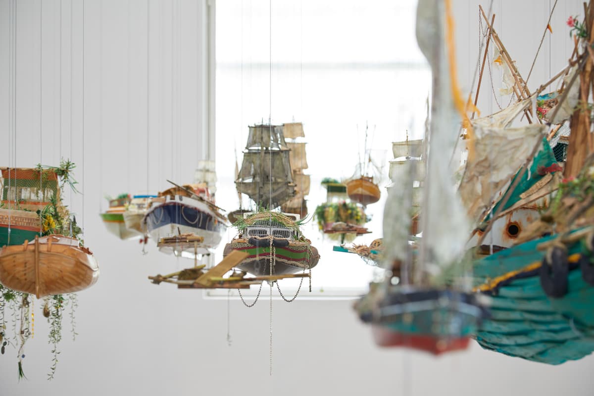 Detailed model of an old sailing ship against a white background with other ships visible in the distance.