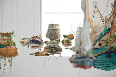Detailed model of an old sailing ship against a white background with other ships visible in the distance.