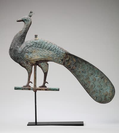 A copper weathervane ornament in the shape of a peacock.