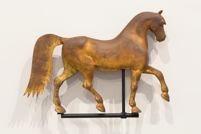 A weathervane in the shape of a horse made of iron and gold leaf.
