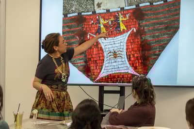 Artist gesturing towards powerpoint presentation in workshop