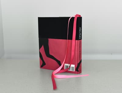 Book with a black and pink cover, featuring dancing figure silhouettes and two pink ribbons.