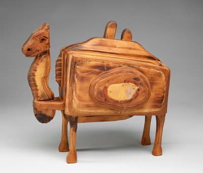 A carved and painted wooden sculpture of a camel.