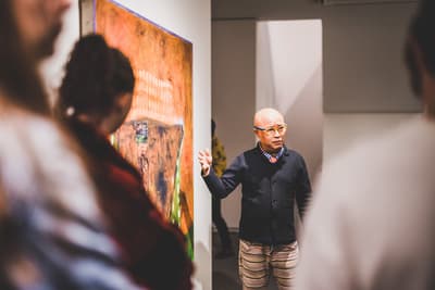 Phong Bui gesturing to painting in front of a group of museum visitors.