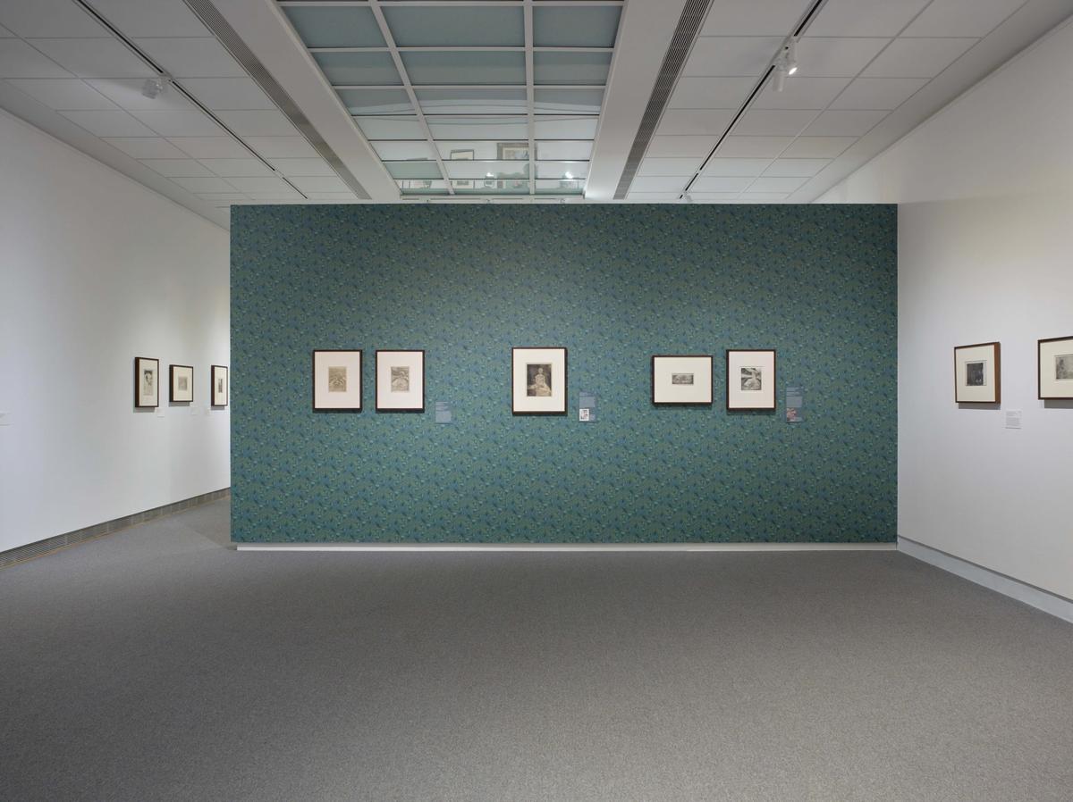 Art gallery with framed paintings on white and green patterned walls.