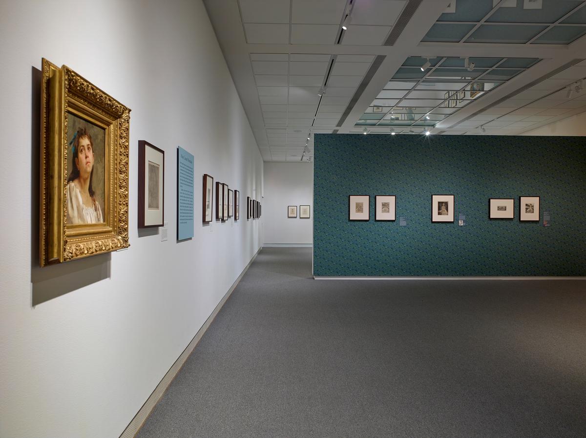 Art gallery with framed paintings on white and green patterned walls.