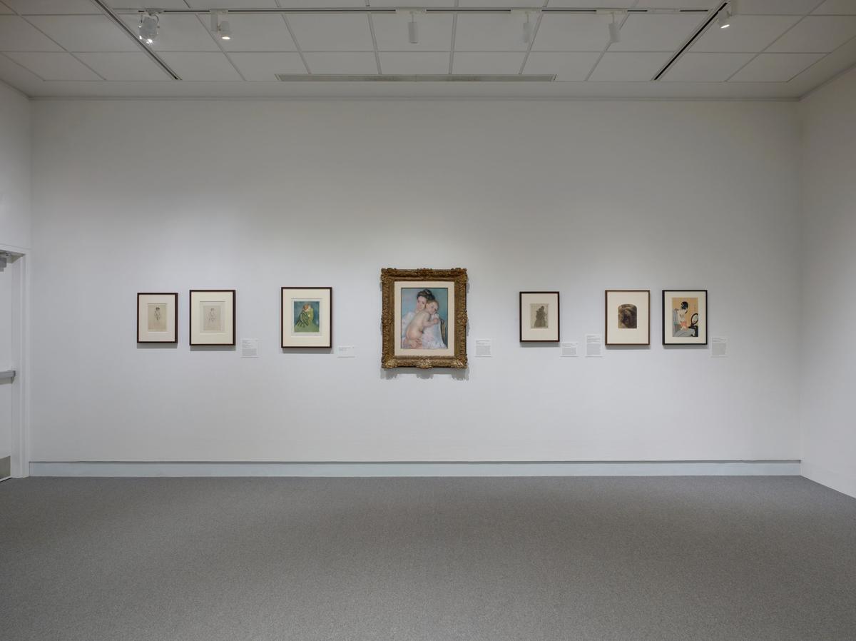 Gallery wall with framed artworks, including a central painting in an ornate frame.