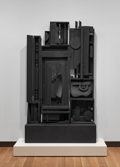 A 1959 constructed, wooden sculpture that is painted black by Louise Nevelson.