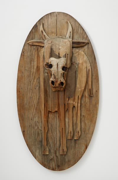 A raw wood relief sculpture of a bull.