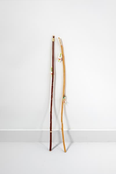 Two painted bronze, string and wire upright sculptures resembling tall walking sticks.
