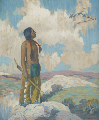 A man with braided hair holding a bow, standing on a rocky landscape, looking up at birds in the sky.