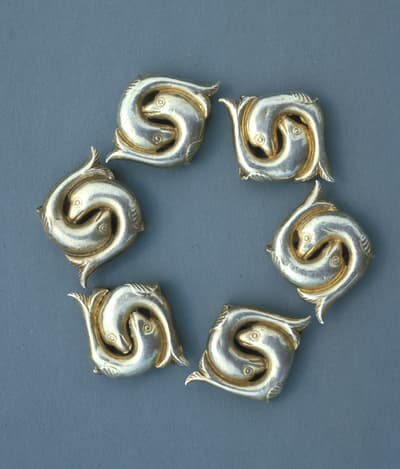 A set of fishes carved out of silver positioned in a circle.