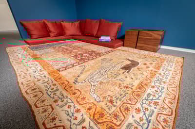 Installation view of "The Sea in a Jug: The Welch Collection of Islamic and Later Indian Art" with cushions and a designed rug.