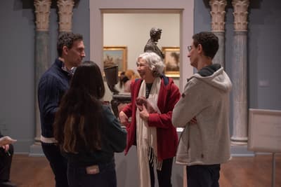 Four museum visitors standing in a tight circle talking