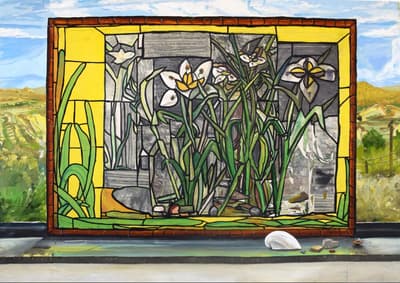 Stained glass pane depicting white lily flowers on top of a gray and yellow background. Image taken at a window with a background view of a desert.