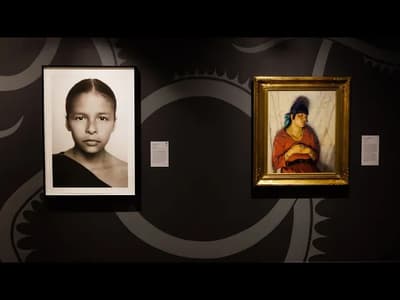 Two artworks displayed on a dark wall; a black-and-white photo on the left and a colorful portrait painting on the right.