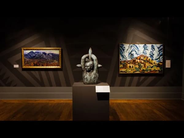 Art gallery with a sculpture and two landscape paintings on display.
