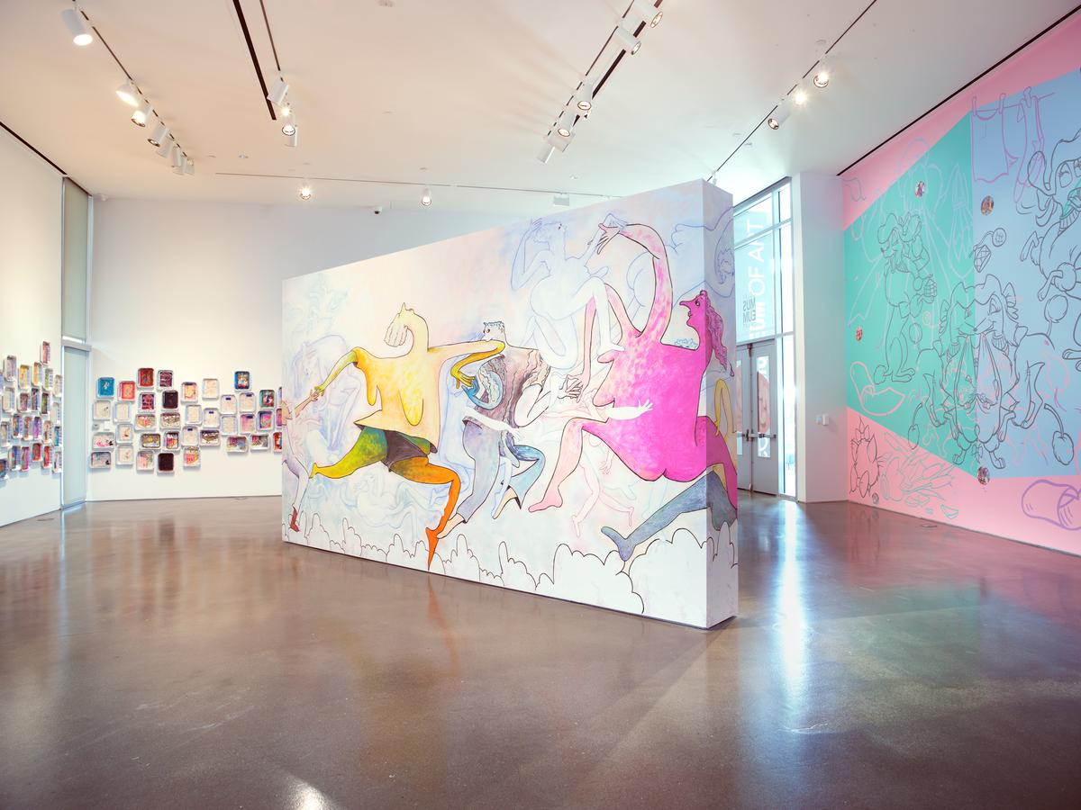 Art gallery with colorful abstract murals on walls and a polished concrete floor.