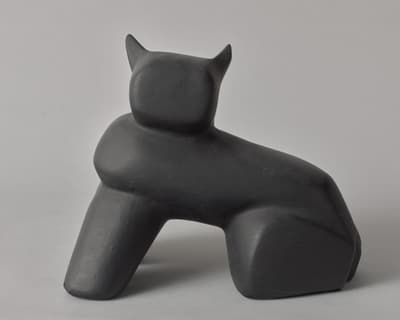 A black, painted, monochromatic plaster sculpture of a cat by Louise Nevelson, circa 1930s.