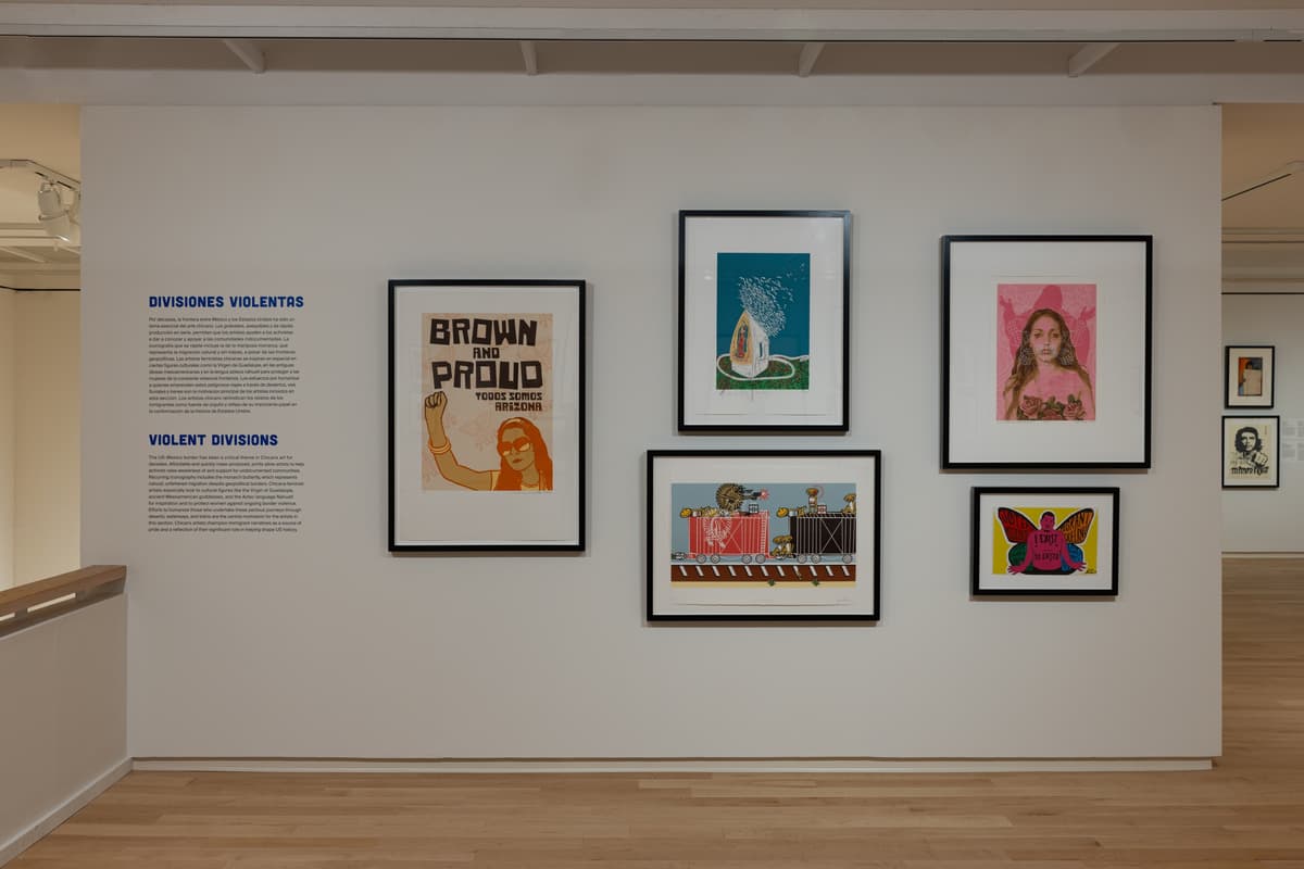 Wall installation titled “Violent Divisions” featuring six framed prints, including posters with slogans and stylized illustrations