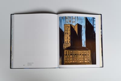 Open book displaying two pages, one with a abstract/cubist style painting of a city and the other containing caption information for the painting