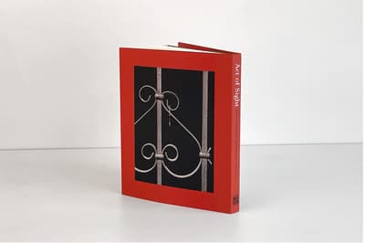 Act of Sight: The Tsiaras Family Photography Collection publication standing on tabletop displaying back cover